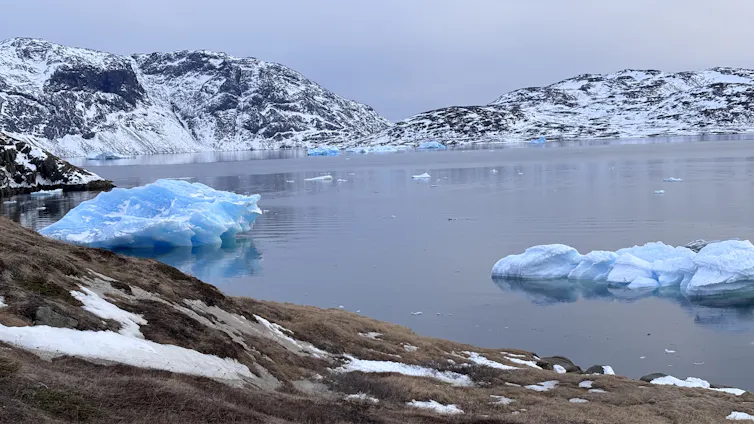 Icebergs floating by and snowed mountain tops along the Narsaq shoreline in South Greenland.