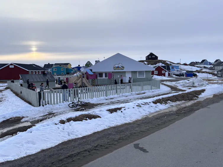 Children play in a daycare in the village of Narsaq in South Greenland, surrounded by colourful houses and snow.