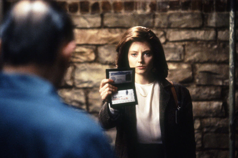 FBI trainee Clarice Starling shows her badge to convicted killer Hannibal Lecter in a prison scene.