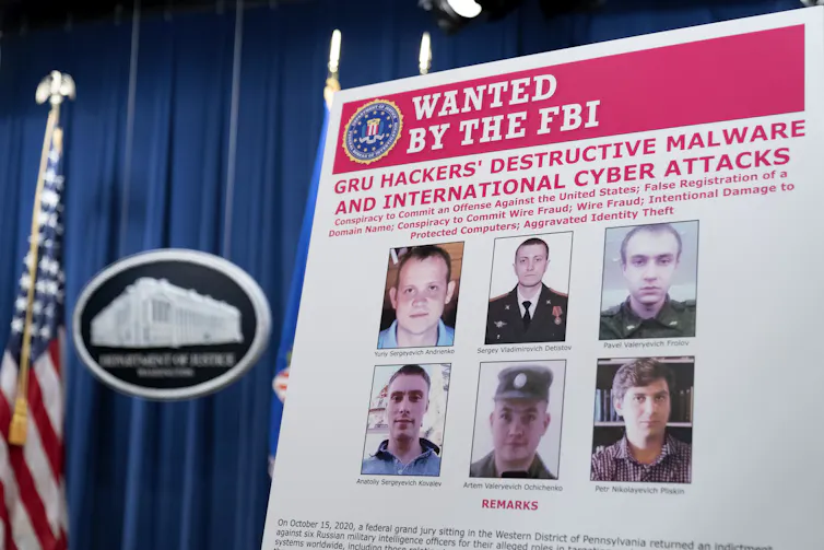 A poster shows the photos and names of six Russian military intelligence officers