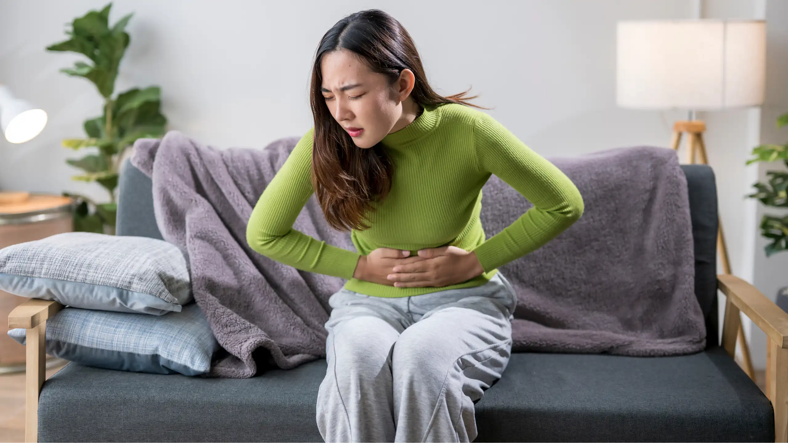 Une femme se tient le ventre de douleur.