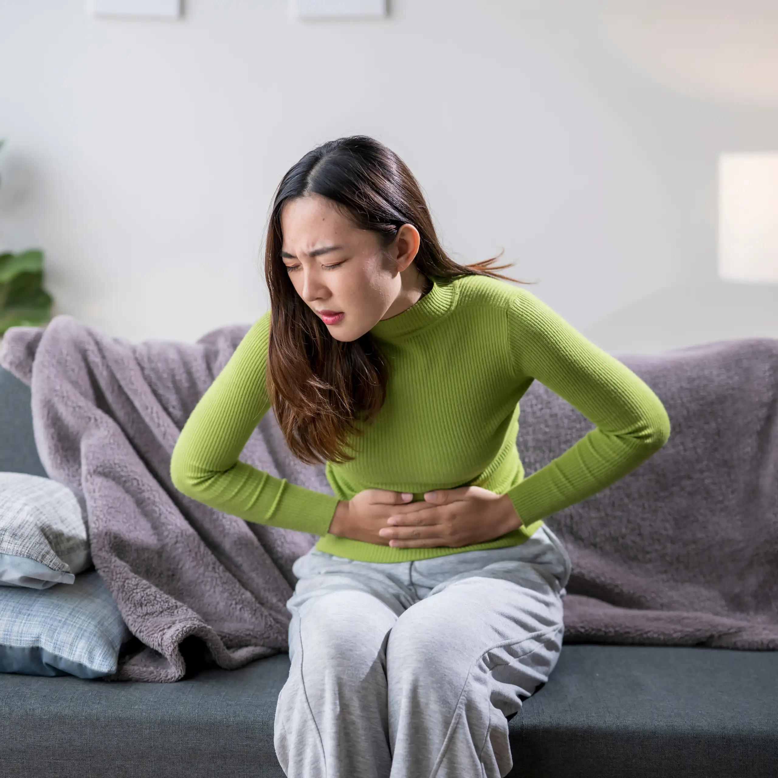 Une femme se tient le ventre de douleur.