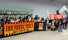 People standing with banners stating 'End Fossil Fuels', 'Pay Up' and 'Phase Out'
