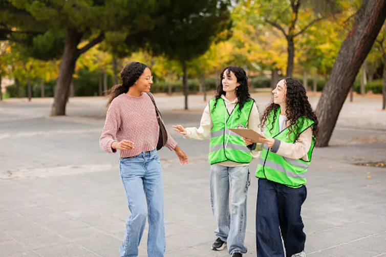 Two young women volunteers talking with a smiling young woman