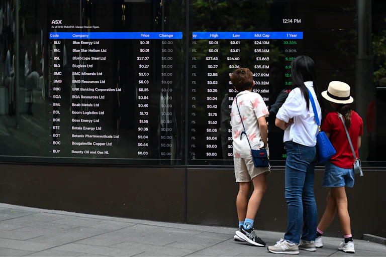 Pedestrians look at a screen showing stock information at the Australian Securities Exchange (ASX)
