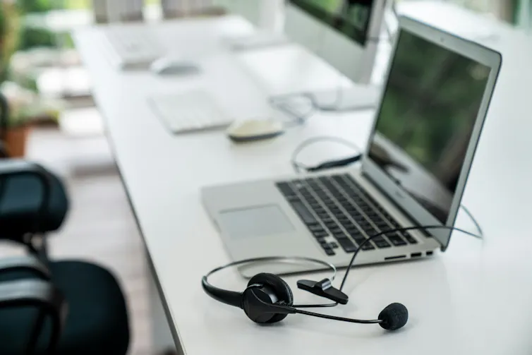 A desk with a computer and a headset.