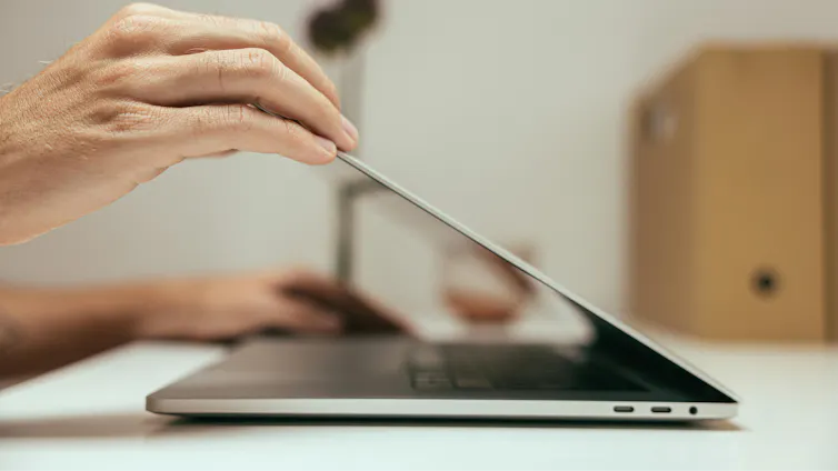 Close up of a person closing a laptop.