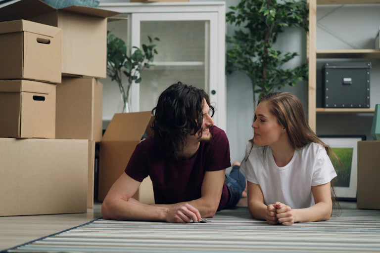 Young couple in empty house surrounded by moving boxes