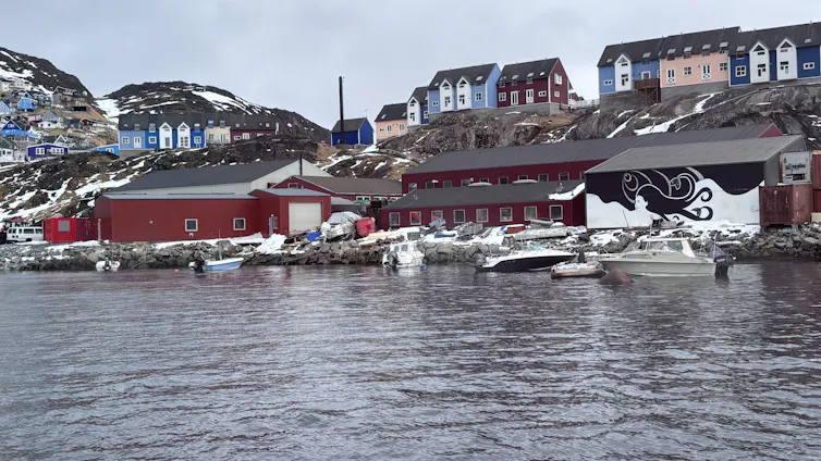 A black and white painting of a woman and the ocean on the back of a building on the banks of Narsaq, South Greenland.