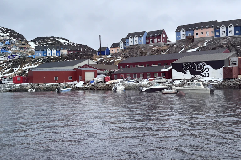 A black and white painting of a woman and the ocean on the back of a building on the banks of Narsaq, South Greenland.