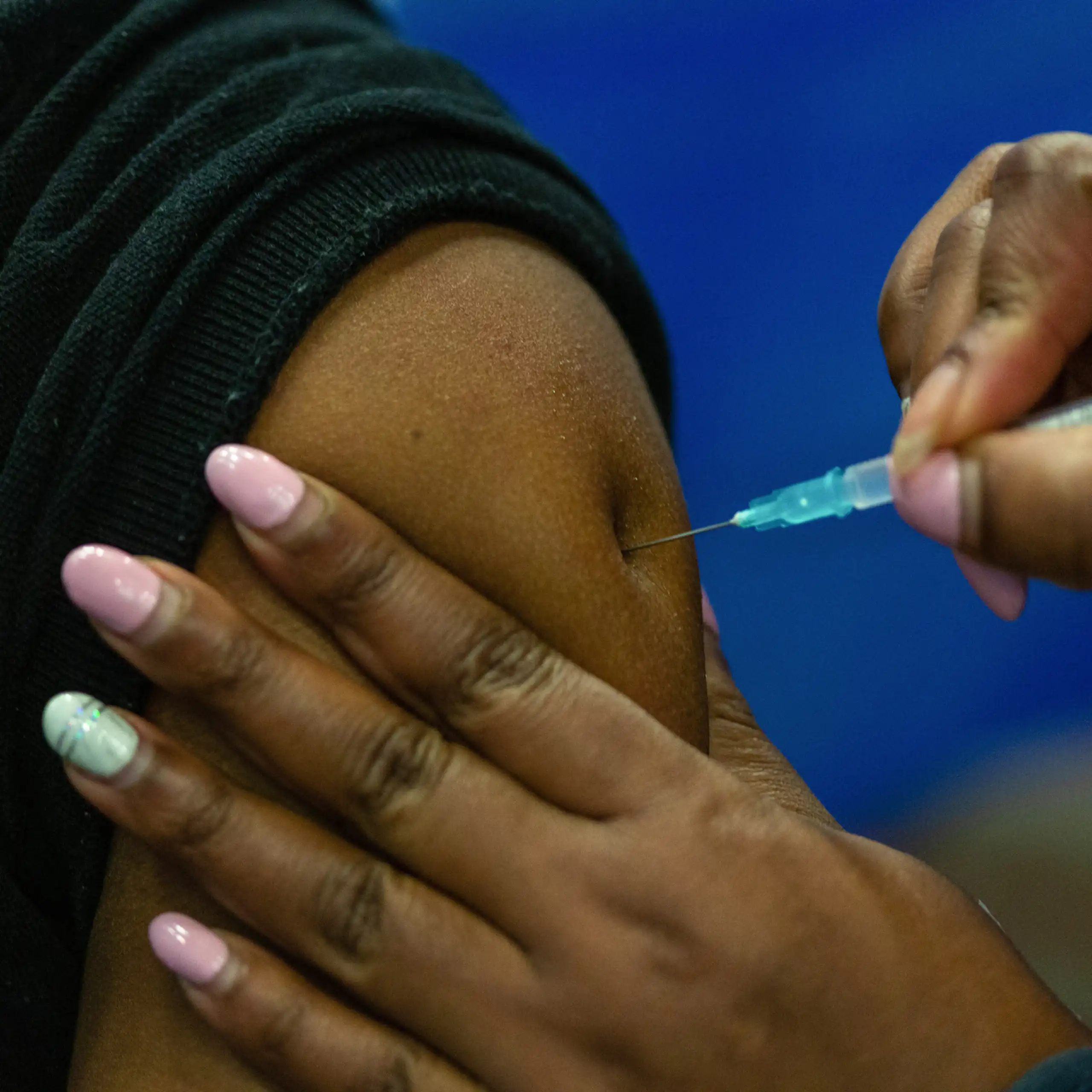 A person receives an injection with a needle in their upper arm