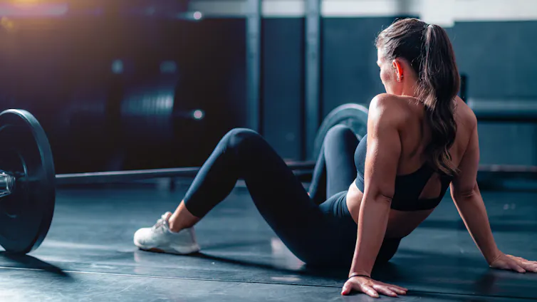 Even most sensible athletes skip stretching – what amateurs can be informed from the elites who combat with restoration routines 1 A woman rests on the floor behind a barbell.