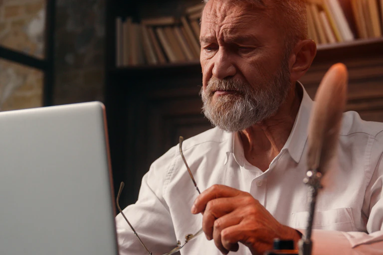 An older man looking with concern at a laptop