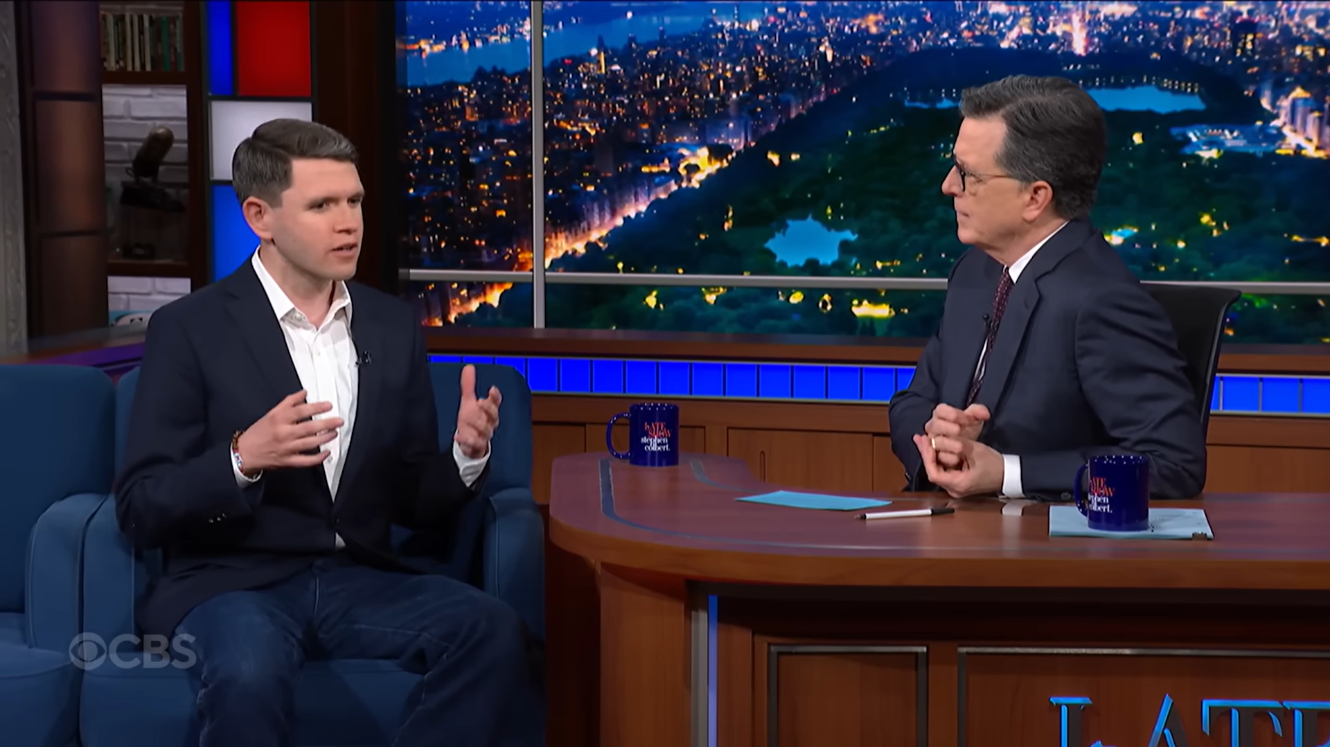 Two men talking on stage late at night.