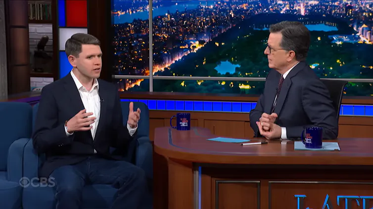Dos hombres hablan en el escenario de un late night.