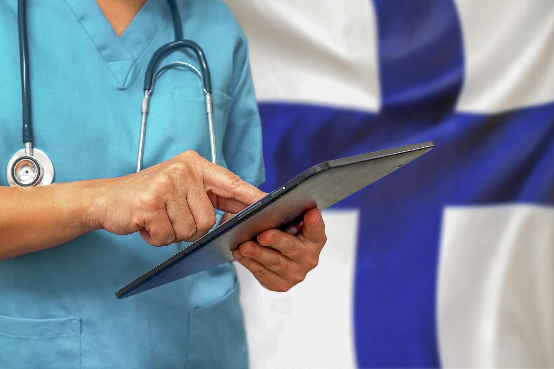 Doctor typing on tablet with a Finnish flag background