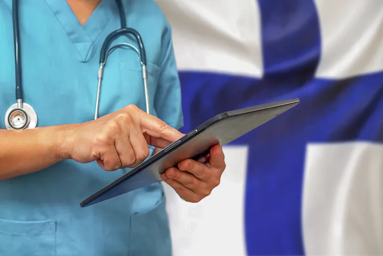 Doctor typing on tablet with a Finnish flag background