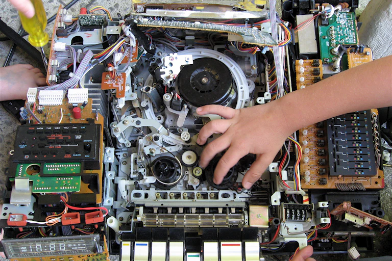 a hand reaching into the exposed insides of an electronic device