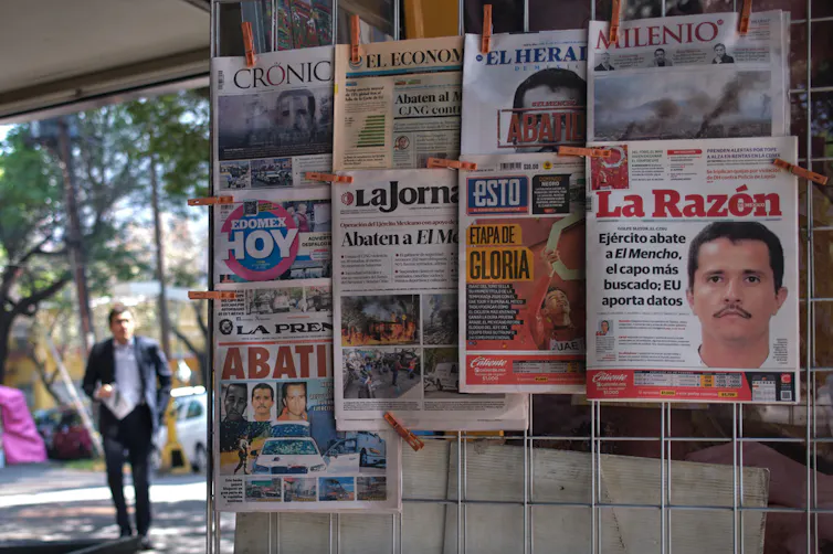 Newspapers hang on display at a kiosk.