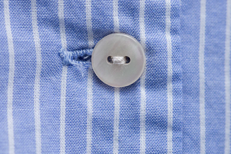 Closeup view of a white button against blue-and-white striped textile