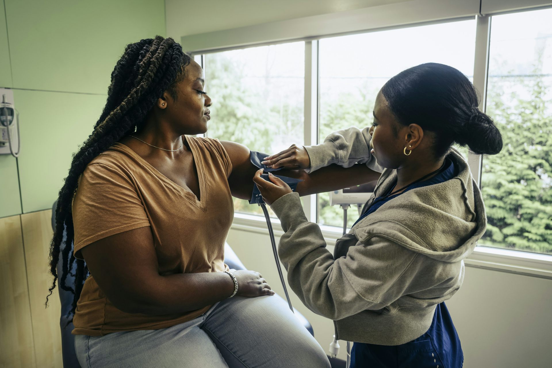 A Black female patient getting a blood pressure cuff put on her arm.