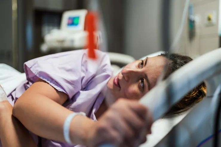 A white woman lies on her side in a hospital bed.