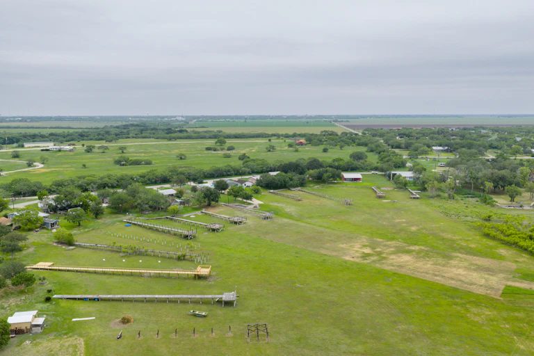 An aerial view of a grassy area with dock structures extending out into it.