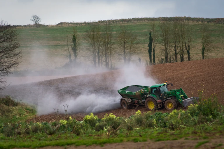 A tractor spreading rock dust on a field
