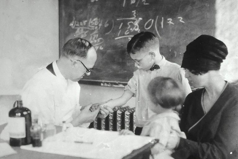 Young boy receiving the Schick Test from a doctor. Boy is accompanied by mother and younger sibling (1915). The Schick Test is a measure of immunity to diphtheria.