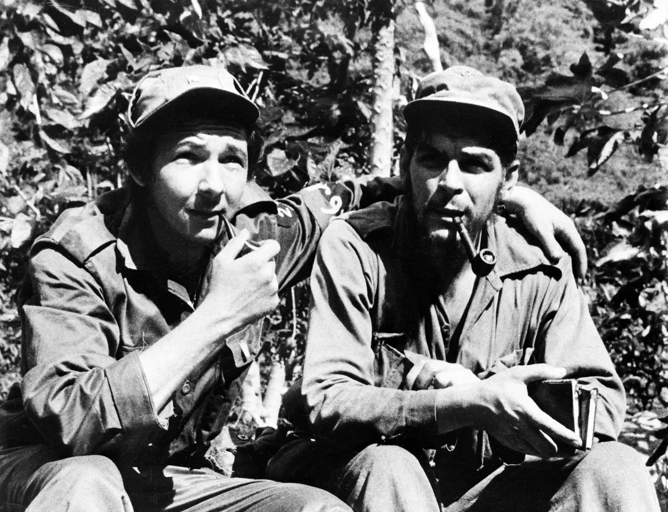 A black and white image of two soldiers sitting together in a jungle.