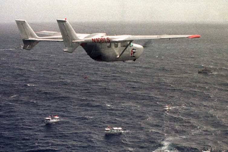 A military plane flies over the ocean