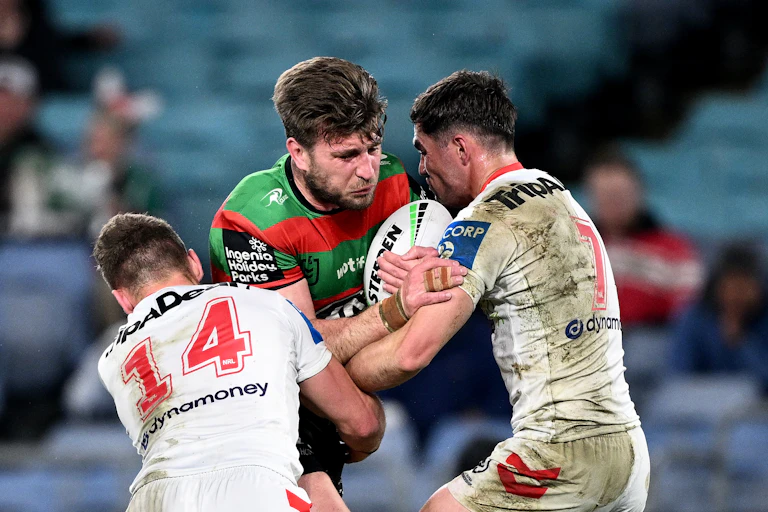 Jai Arrow (centre) with ball being tackled by two players.