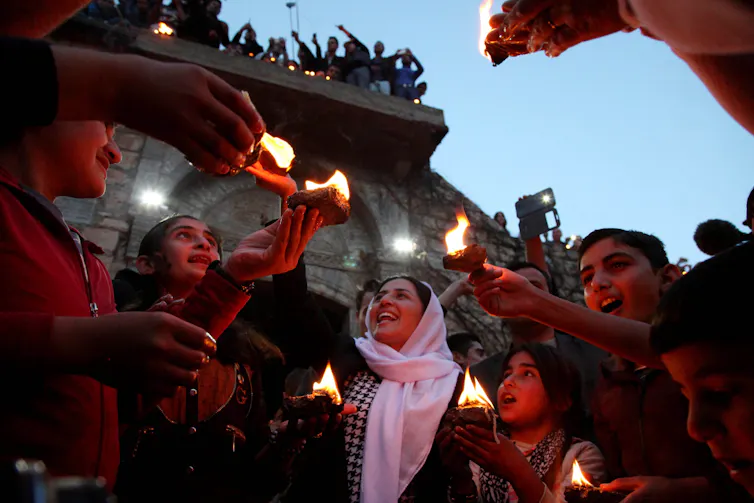 Young people hold flames at dusk.