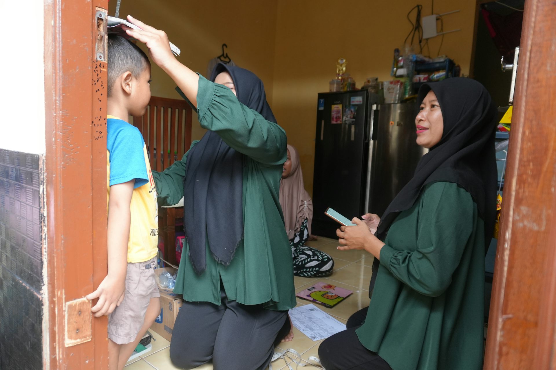 Kader posyandu saat cek gizi anak sembari melakukan pencatatan lewat aplikasi PN-PRIMA.