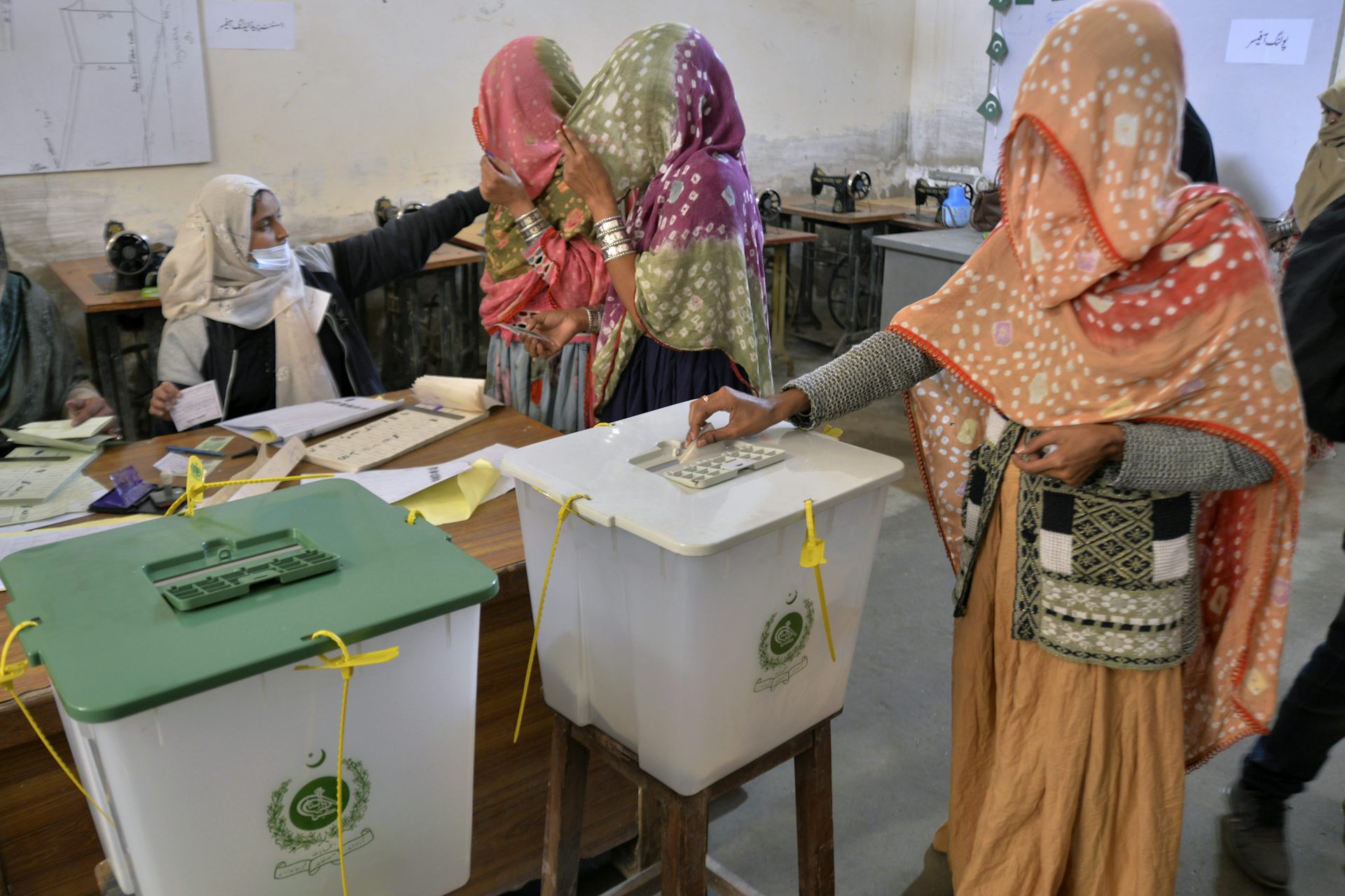 Mujeres con velos coloridos votan en un colegio electoral.