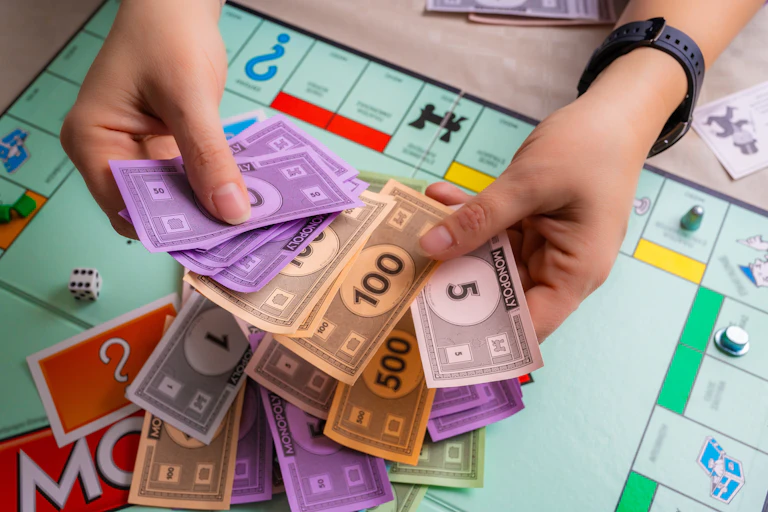 Unas manos muestran billetes del Monopoly sobre un tablero del juego