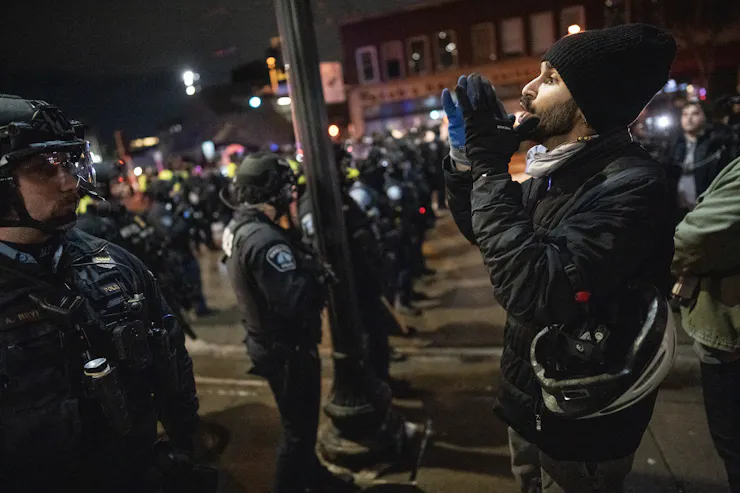 A man dressed in black faces dozens of police officers.