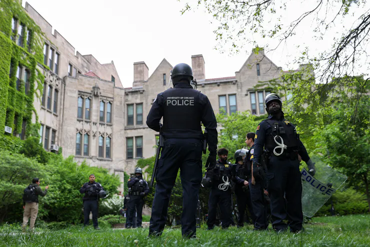 Police stand on the grounds of a college campus.