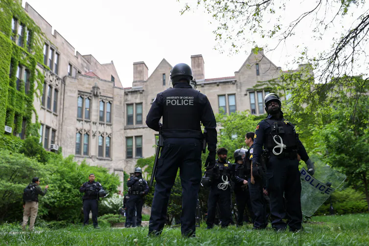 Police stand on the grounds of a college campus.