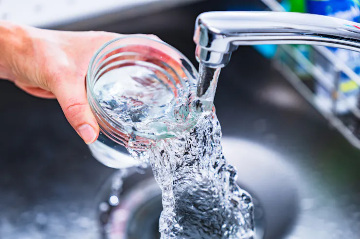 Hand filling glass with water from a faucet