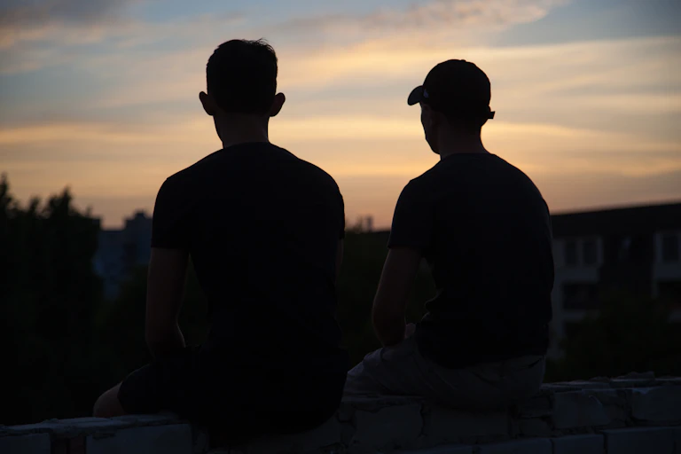Silhouette of two male friends at sunset