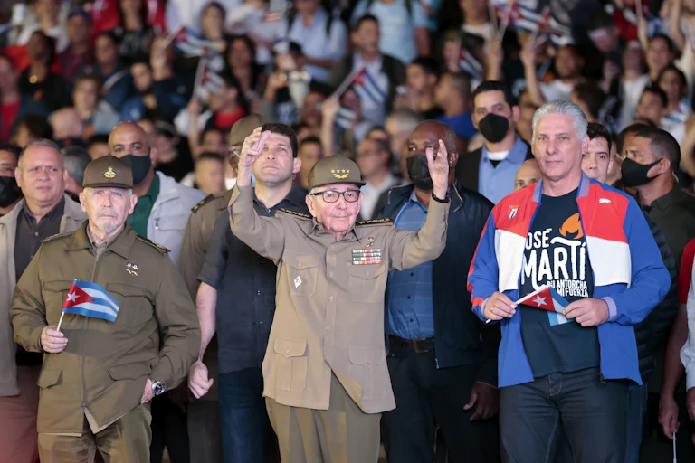 Raúl Castro holds his hands aloft at a rally alongside Miguel Díaz-Canel.