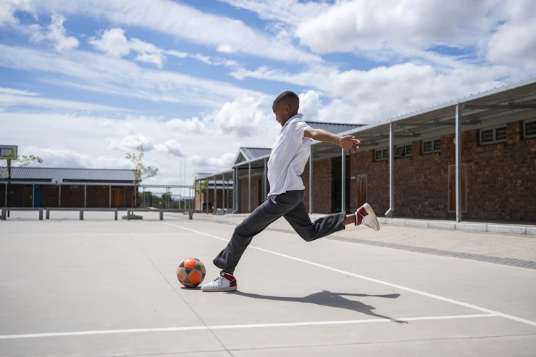 Boy kicking a ball in a school setting