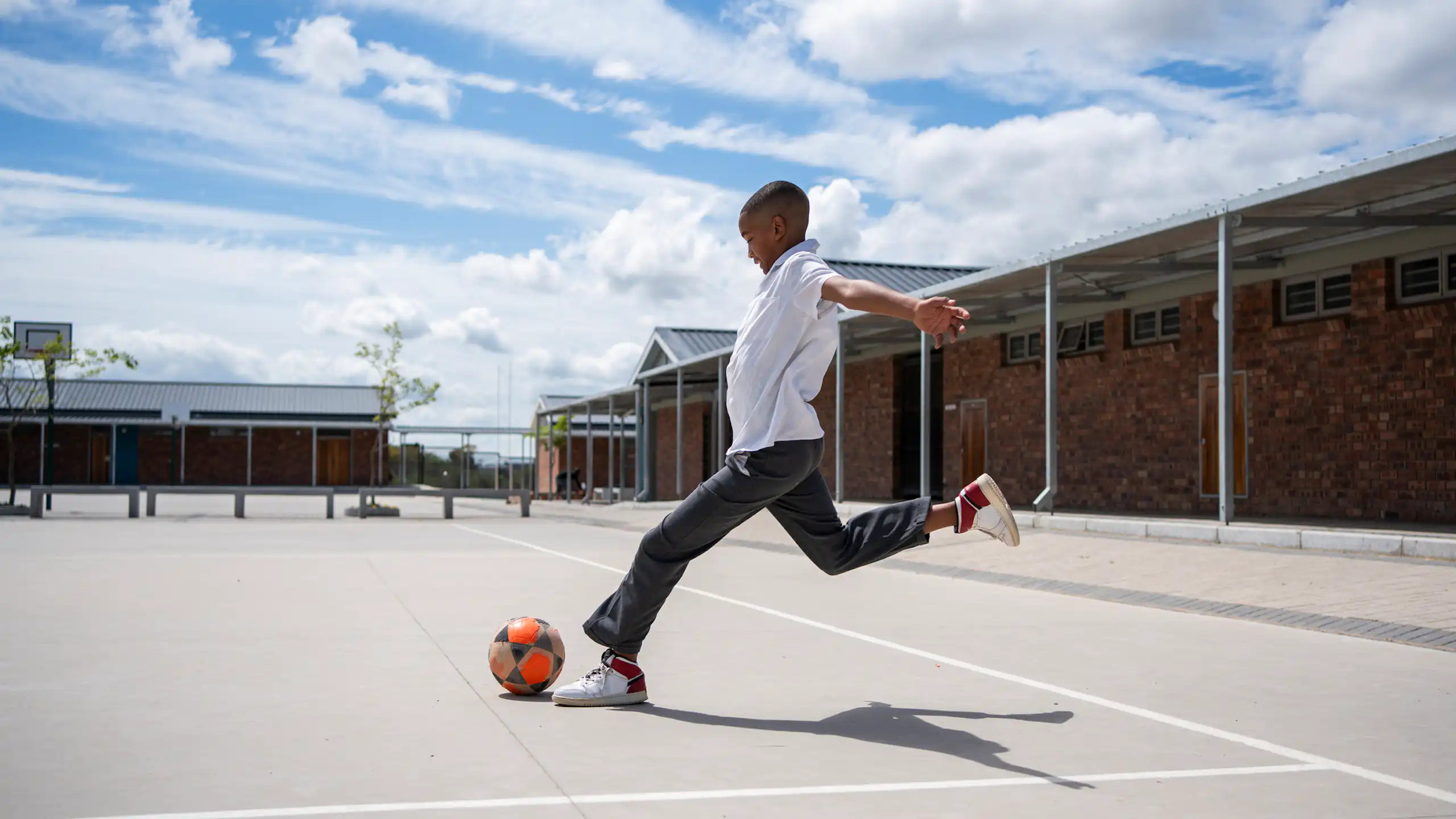 Boy kicking a ball in a school setting