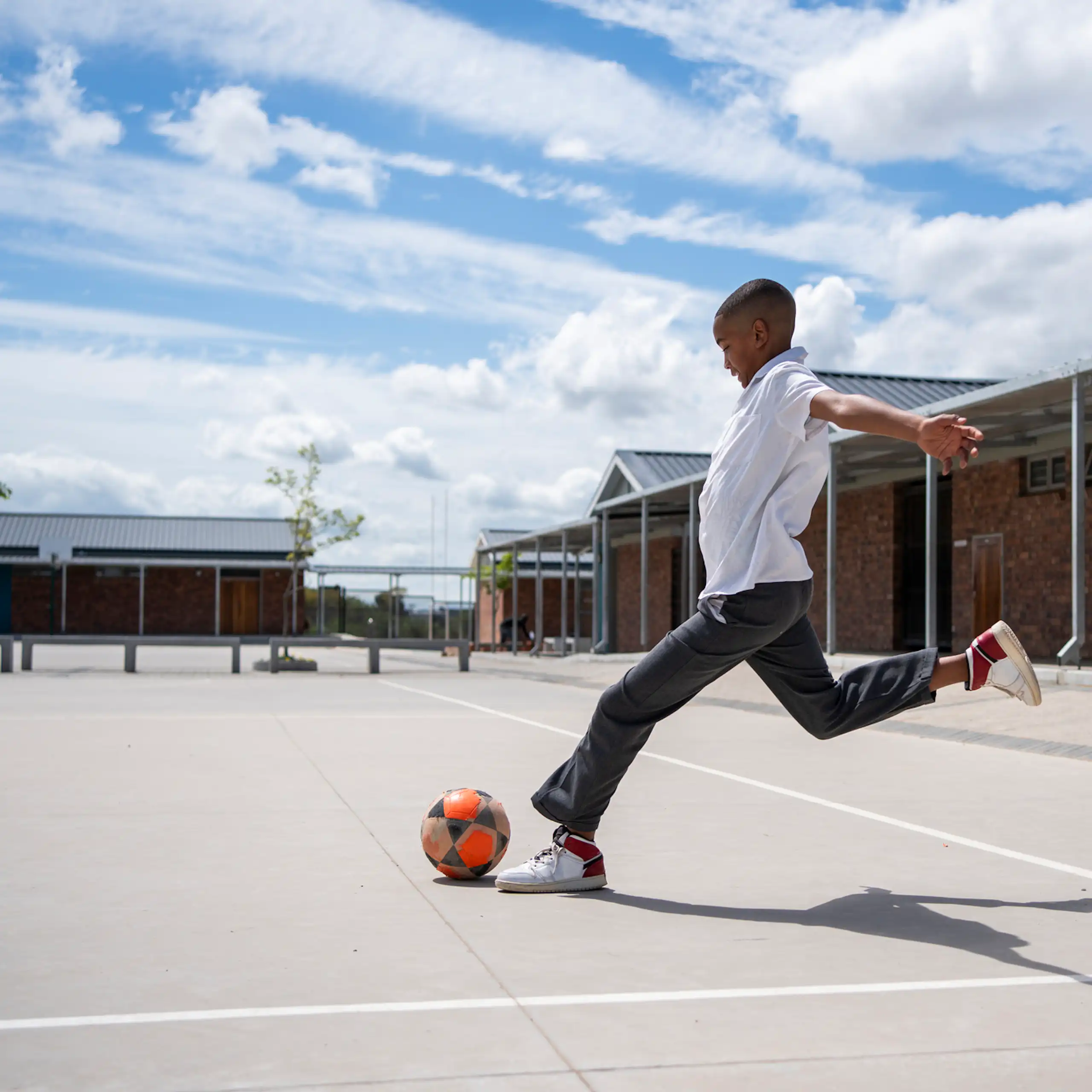 Boy kicking a ball in a school setting
