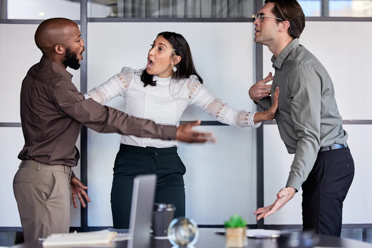 Dos hombres y una mujer discutiendo acaloradamente en el trabajo