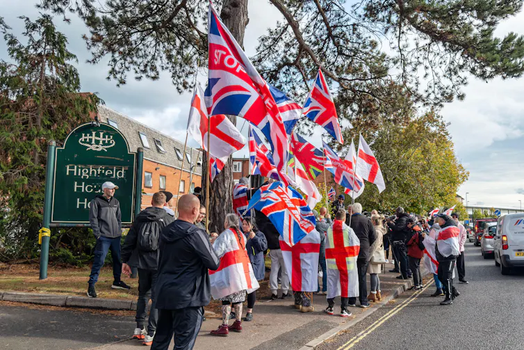 Protesters draped in UK and St George's flags outside a hotel housing asylum seekers