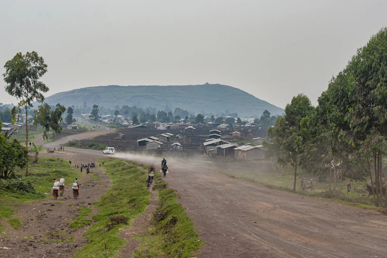 Unpaved road with small buildings and hill in the distance