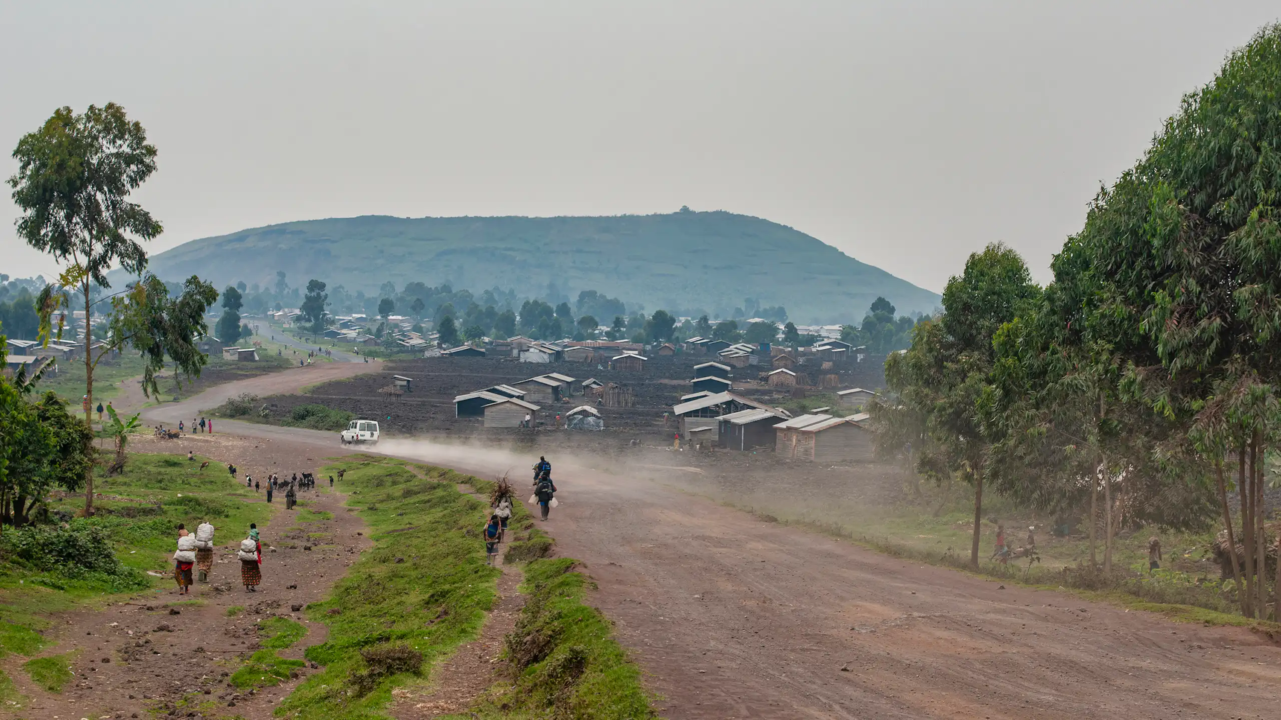 Unpaved road with small buildings and hill in the distance
