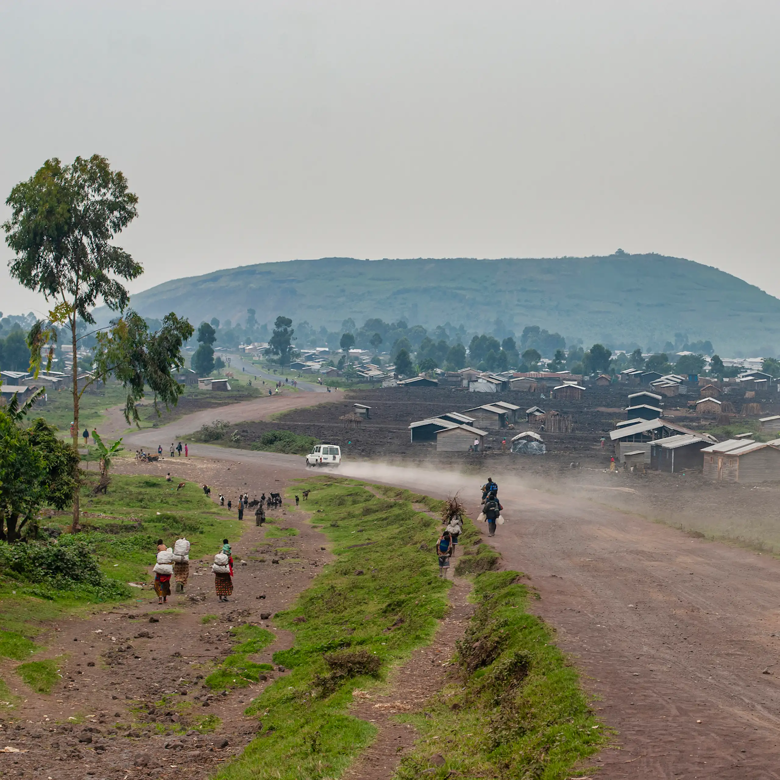 Unpaved road with small buildings and hill in the distance